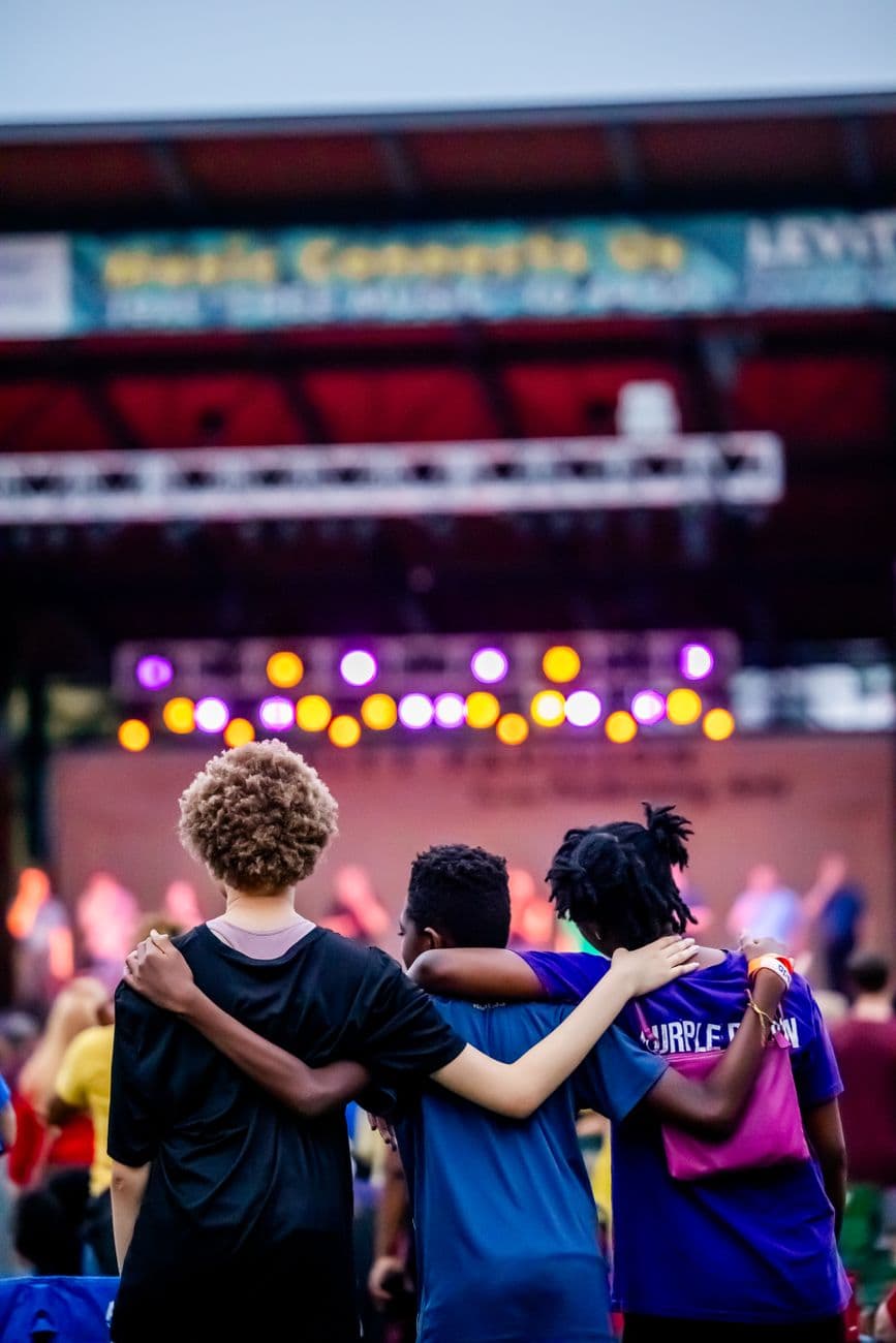 A group of teenagers enjoying a concert with colorful stage lights creating a lively atmosphere.