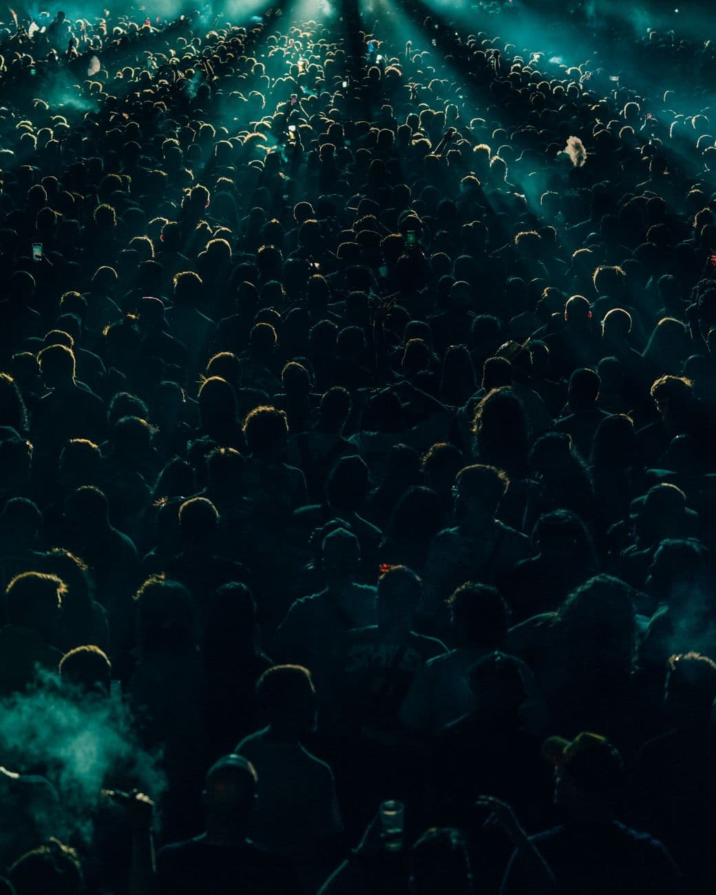 A dense crowd enjoys a lively concert at night with dramatic lighting creating shadows and an energetic atmosphere.