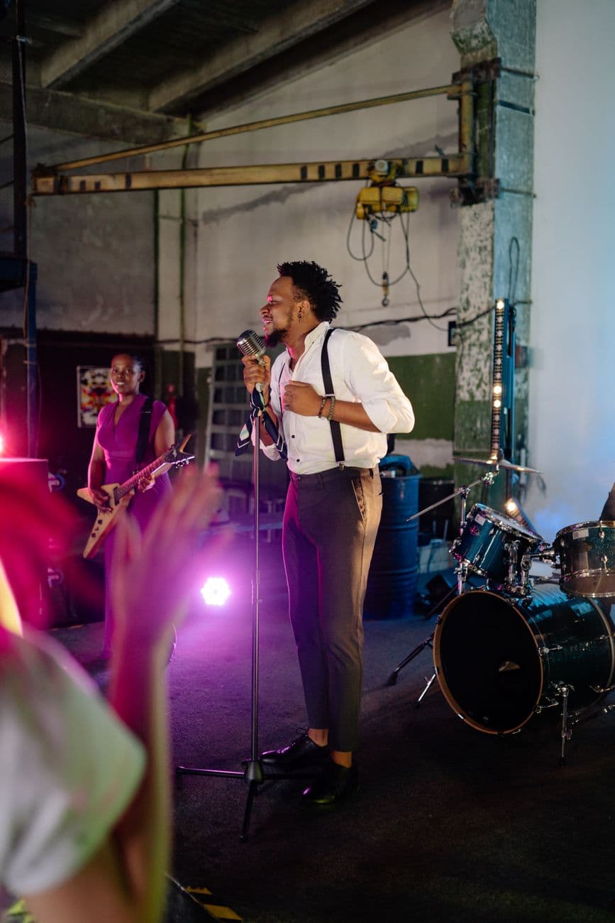 Energetic band performance indoors featuring a lively singer and guitarist under vibrant lighting.