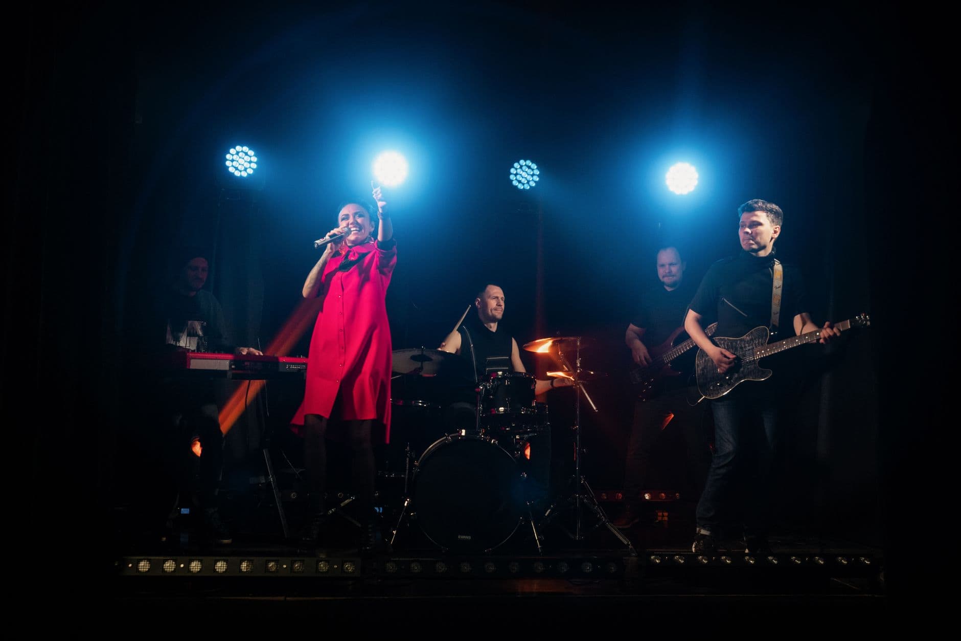 A vibrant live band playing instruments with dynamic stage lighting creating an energetic atmosphere.