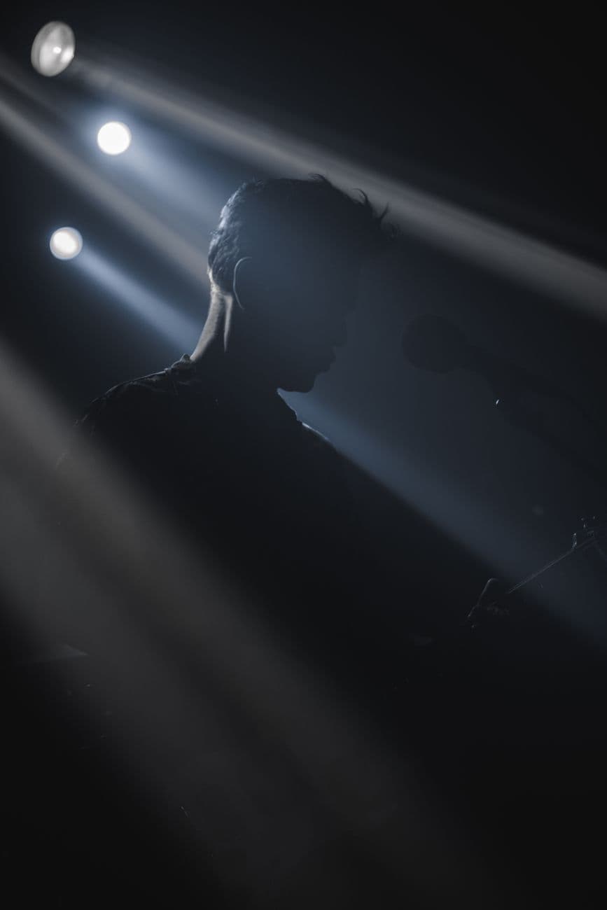 A captivating silhouette of a musician under dramatic stage lights, creating a moody concert atmosphere.