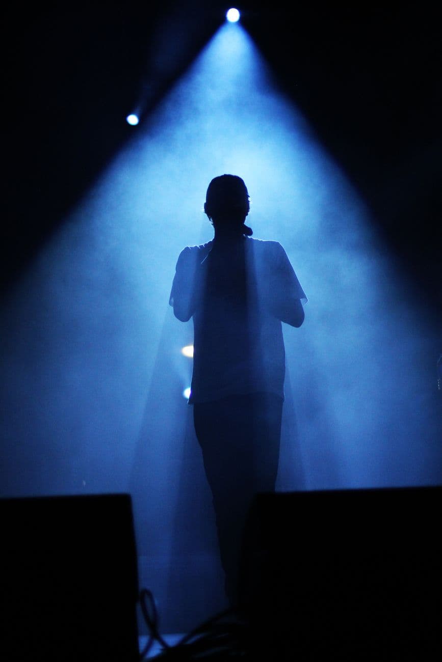 Captivating silhouette of a live performer in blue stage lighting, creating a dramatic concert atmosphere.